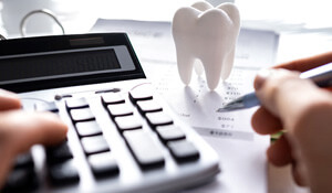 patient calculating cost on desk with prop tooth