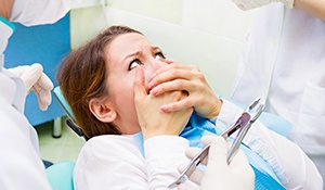 anxious woman covering her mouth in the dentist’s chair