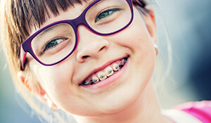 young girl sporting glasses and braces smiling