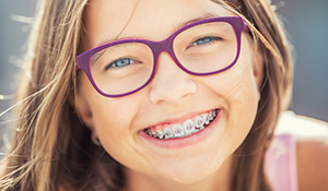 Young child with glasses and braces smiling brightly
