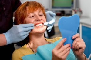 An older woman viewing her new dental implants.